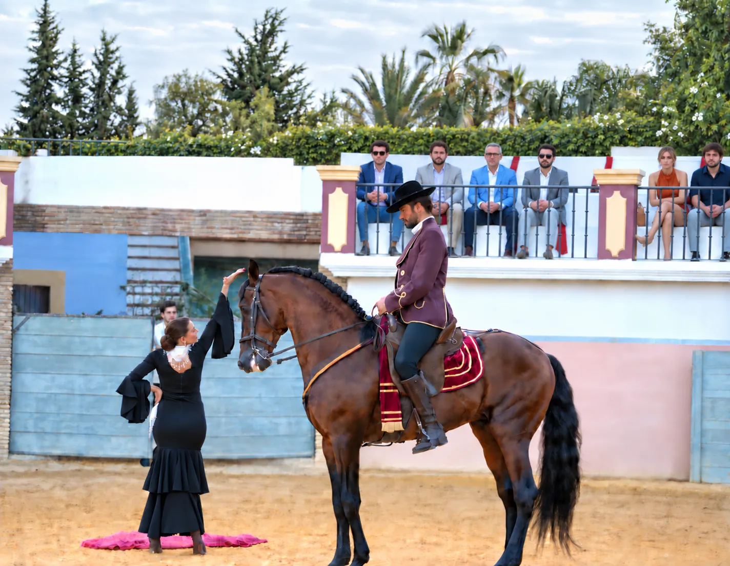 Espectáculo ecuestre en un picadero, con un jinete vestido de corto y una bailaora de flamenco ante las gradas